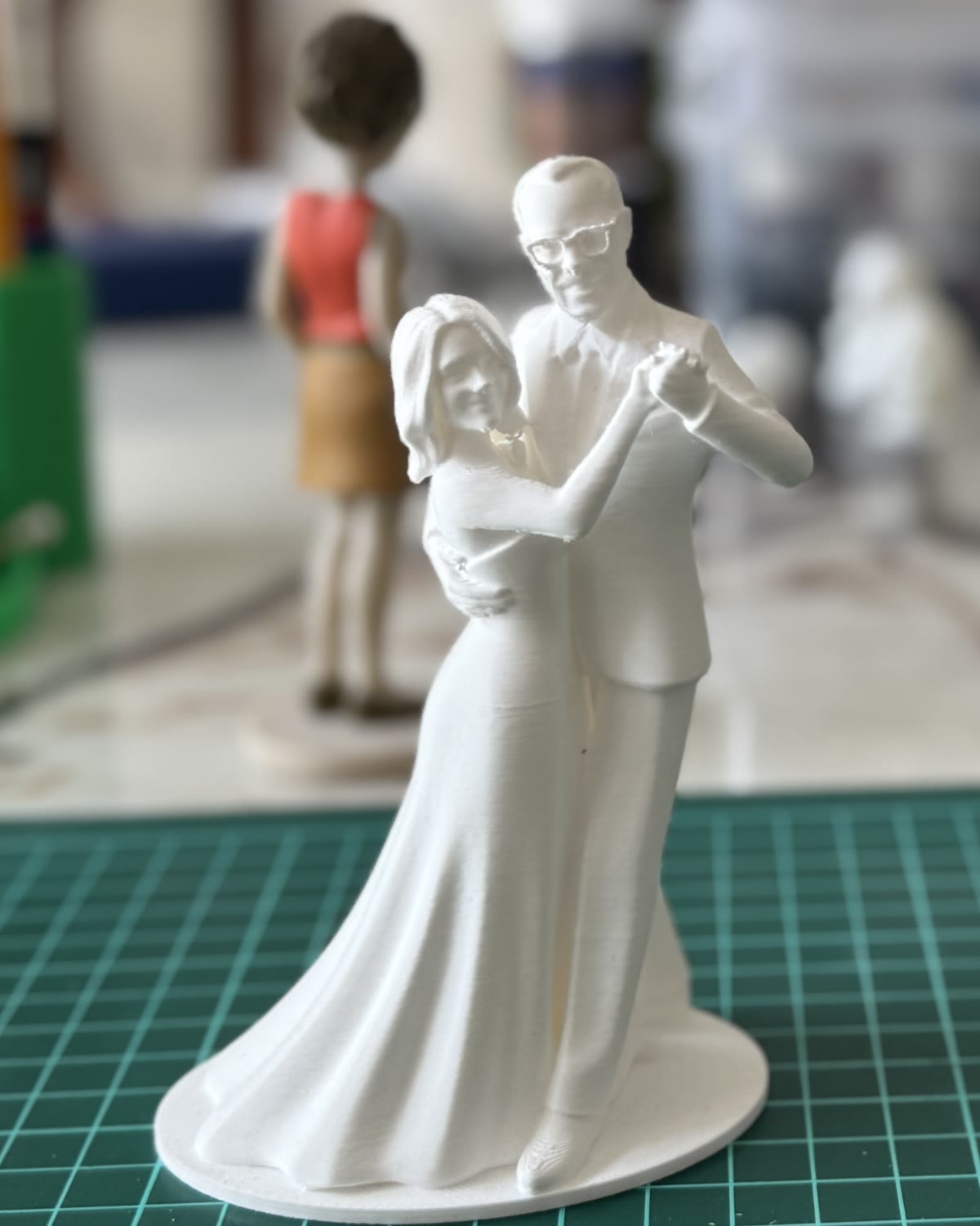 Figurine de mariés en résine blanche, les deux enlacés dans une pose de danse
