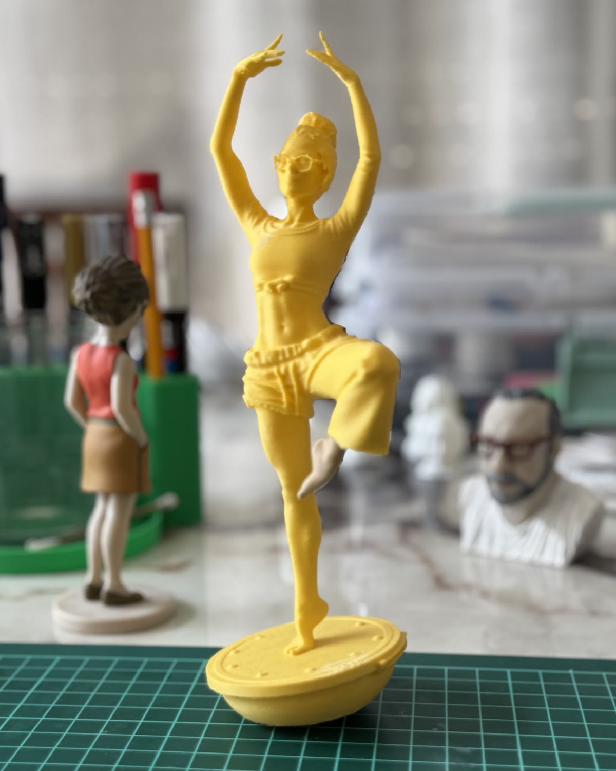 La figurine imprimée en résine, posée sur le tapis de découpe de l'atelier